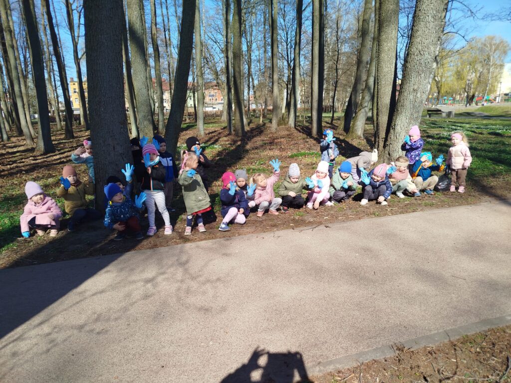 dzieci stoja w parku miesjkim, postanowiły wziąc udział w akcji sprzątania świata z oakzji DNIA ZIEMI 